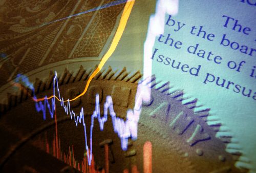 Composite image of a financial graph with fluctuating blue and orange lines, overlaid on a close-up of text from an official document and part of a coin. The text in the background reads: 